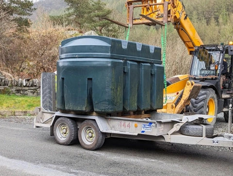 Ein alter Heizöl-Tank wird von einem Kran abtransportiert.
